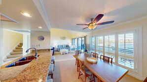 A spacious kitchen with a granite countertop, a dining area with a wooden table, and a ceiling fan. - Lakeside Retreat in Gated Litchfield by the Sea (Pawleys Island)