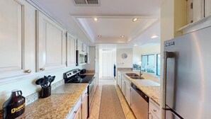 A modern kitchen with white cabinetry, granite countertops, stainless steel appliances, and a central island. - Lakeside Retreat in Gated Litchfield by the Sea (Pawleys Island)