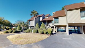 A row of townhouses with a covered driveway and well-maintained lawns. - Lakeside Retreat in Gated Litchfield by the Sea (Pawleys Island)