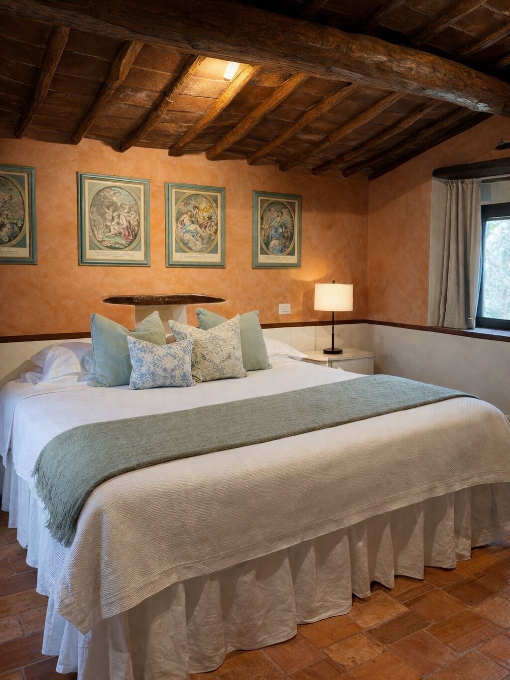 A bedroom with a large bed, a nightstand, a lamp, and framed artwork on the wall.