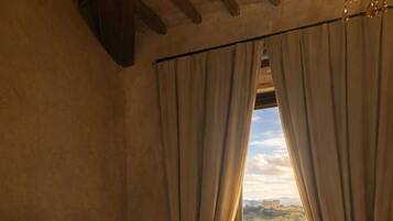 Une chambre à coucher avec un lit, un radiateur, des rideaux et une vue sur la verdure à l’extérieur.