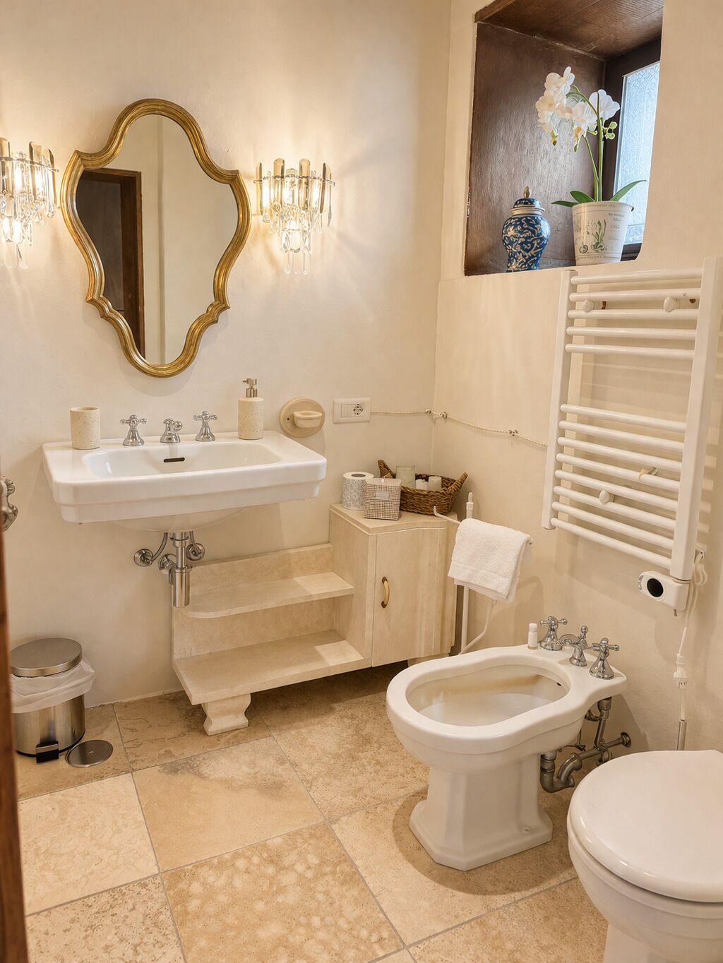 A bathroom with a pedestal sink, a freestanding toilet, a bidet, a vanity with a mirror, and a towel rack.