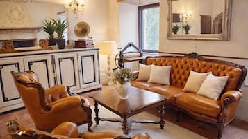 Un salon traditionnel avec un canapé en cuir, des fauteuils assortis, une table basse en bois, un gramophone ancien et un grand miroir.