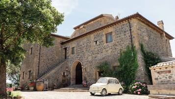 Ein Steinhaus mit einer Rezeption und einem Oldtimer vor der Fassade.
