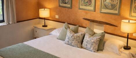 A spacious bedroom with a large bed, two bedside tables, and a wooden ceiling.