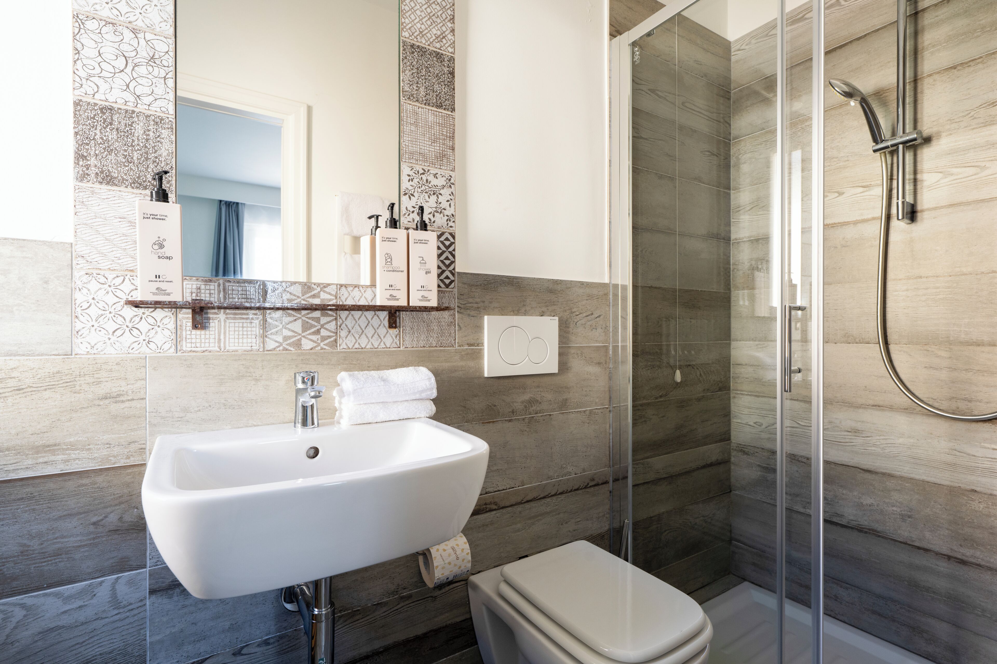 A modern bathroom with a white sink, a toilet, and a glass-enclosed shower.