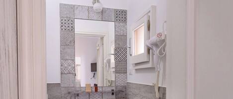 A modern bathroom with a large mirror, a sink, and a shower area.