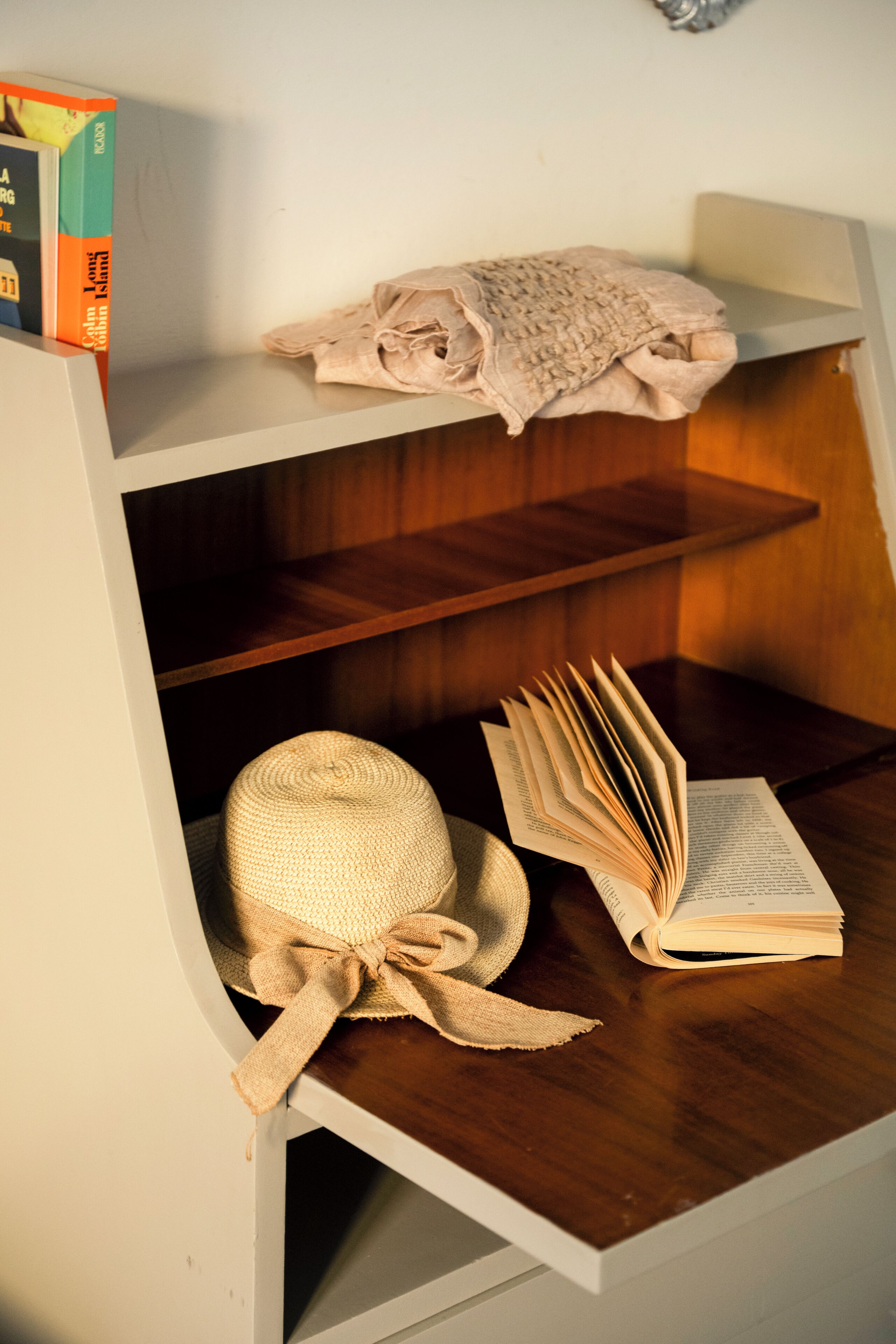 Ein Bücherregal mit einem Buch, einem Hut und einer Schachtel.