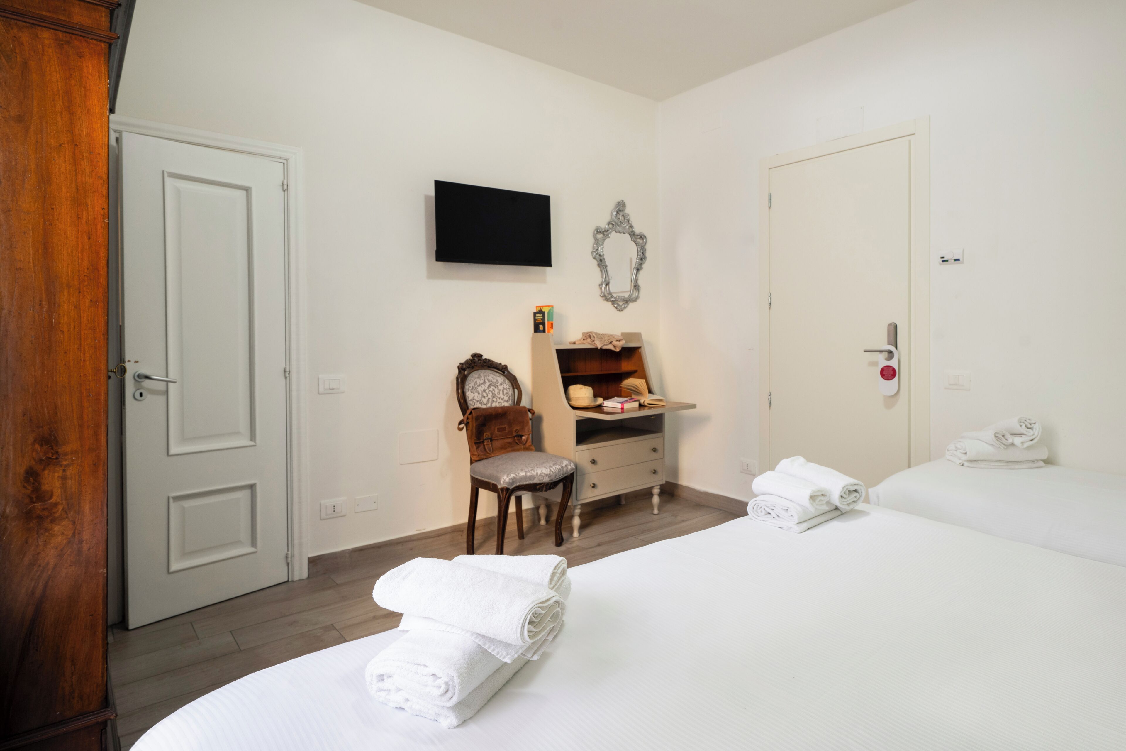 A hotel room with a bed, a chair, a dresser, a television, and a door.