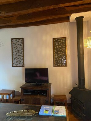 Uma sala de estar com televisão, móvel de entretenimento de madeira, lareira e duas obras de arte emolduradas na parede.