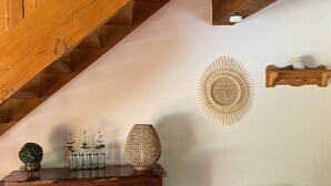 A wooden staircase, a dresser with drawers, a decorative wall clock, a small plant, and a radiator.