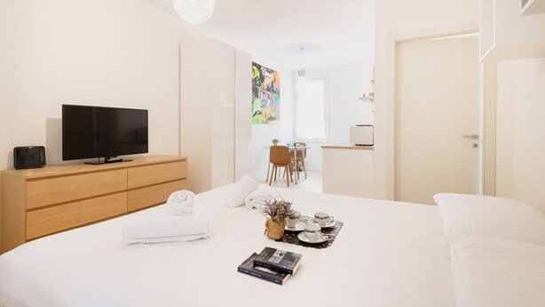 Una habitación de hotel moderna con cama, televisor, escritorio y un cuadro en la pared.