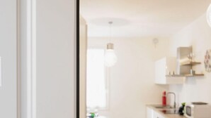 Una cocina moderna con armarios blancos, un microondas y una lámpara colgante.
