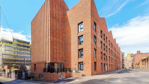 A modern brick building with a unique angular design, featuring multiple windows and a visible entrance. - City Centre Apartment, Quiet and Cozy, Sleeps 4. (Liverpool)