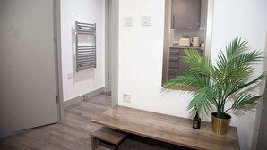A hallway with a wooden bench, a potted plant, and a towel rack. - City Centre Apartment, Quiet and Cozy, Sleeps 4. (Liverpool)