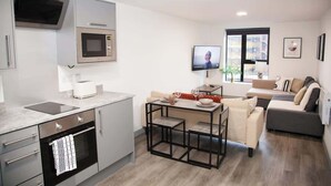 A modern kitchen with a built-in microwave, oven, and a dining area with a table and chairs. - City Centre Apartment, Quiet and Cozy, Sleeps 4. (Liverpool)