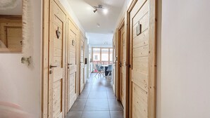A hallway with wooden doors, a tiled floor, and a view of a balcony with chairs. - Ambre blanche - Les Gets - Centre village (Les Gets)