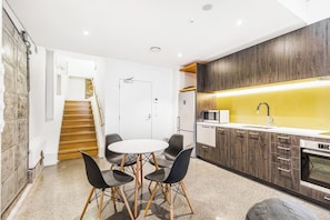 A modern kitchen with a microwave, oven, and wooden cabinets. There is a dining area with a round table and four chairs.