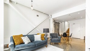 Una sala moderna con sofá, sillón y un comedor con sillas.