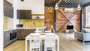 Eine moderne Küche mit Essbereich, einer Ziegelwand und einem Wohnzimmer mit Sofa und Fernseher.