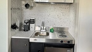 A compact kitchen with a microwave, stove, sink, and a coffee maker. - Location! Location! Lovely Studio in Orlando (Orlando)