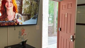A room with a television mounted on the wall, a closed door, and an air conditioning unit above it. - Location! Location! Lovely Studio in Orlando (Orlando)
