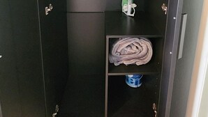 A compact, dark-colored storage unit with a single shelf, a folded towel, and a green cleaning cloth. - Location! Location! Lovely Studio in Orlando (Orlando)