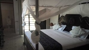 Un dormitorio con cama con dosel, un ventanal grande y cabecera de madera.