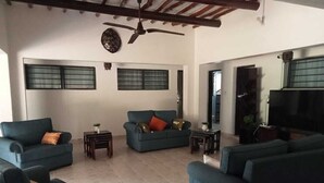 Un salón amplio con ventilador de techo, dos sofás, una mesa de centro y un televisor.