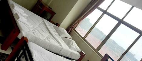 A room with a bed, a window, and a view of the water.