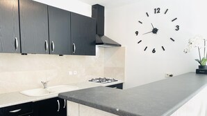 Una cocina moderna con armarios oscuros, una estufa a gas, un fregadero y un reloj de pared.