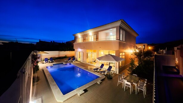 A two-story house with a swimming pool and outdoor seating.