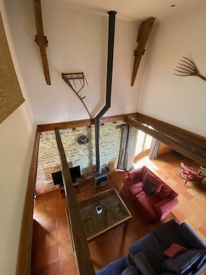 A high-ceiling room with a fireplace, a stone wall, and a red sofa.