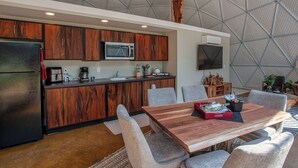 A modern kitchen with wooden cabinets, a microwave, and a dining area with a wooden table and chairs.