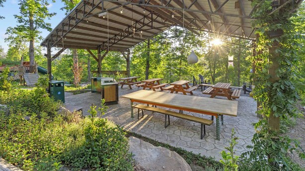 Un patio al aire libre con mesas de picnic y una zona de estar cubierta.