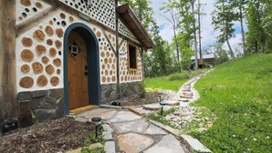 Una casa rústica con fachada de piedra, una puerta de madera y un camino de piedra que lleva a la entrada.