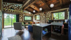 Una cocina rústica con una isla grande, paredes de piedra y ventanas amplias.
