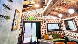 Un interior acogedor con techo de madera, una luz decorativa azul y un papel tapiz estampado.