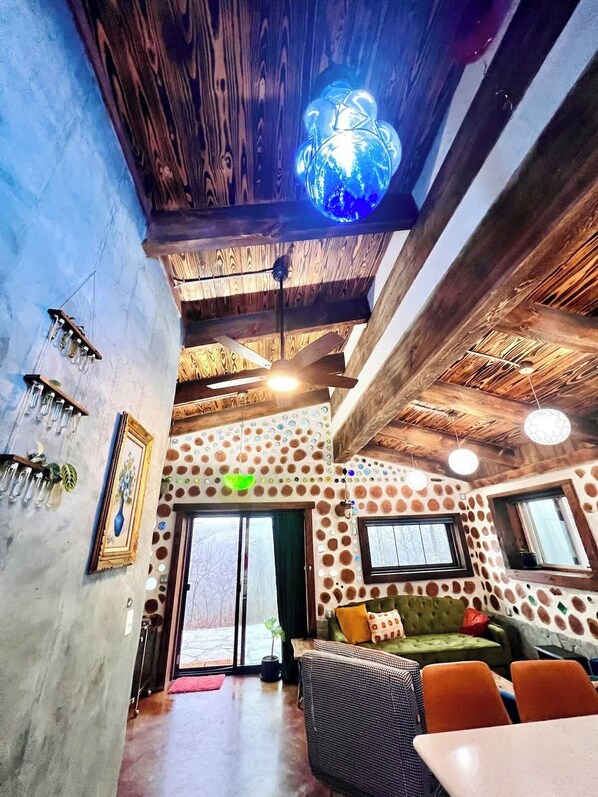 A cozy interior with a wooden ceiling, a blue decorative light, and a patterned wall.
