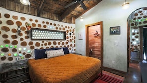 A bedroom with a large bed, a wooden ceiling, and a wall with circular patterns.