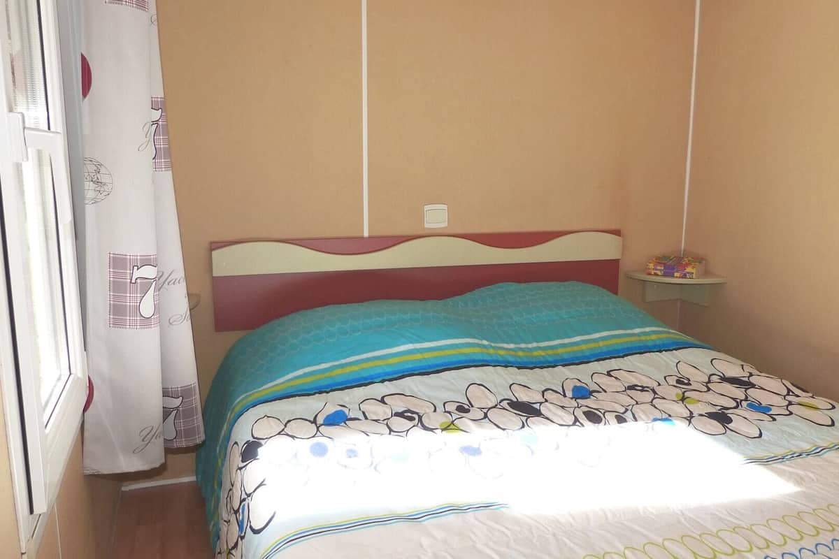 A bedroom with a bed, a nightstand, and a window with curtains.