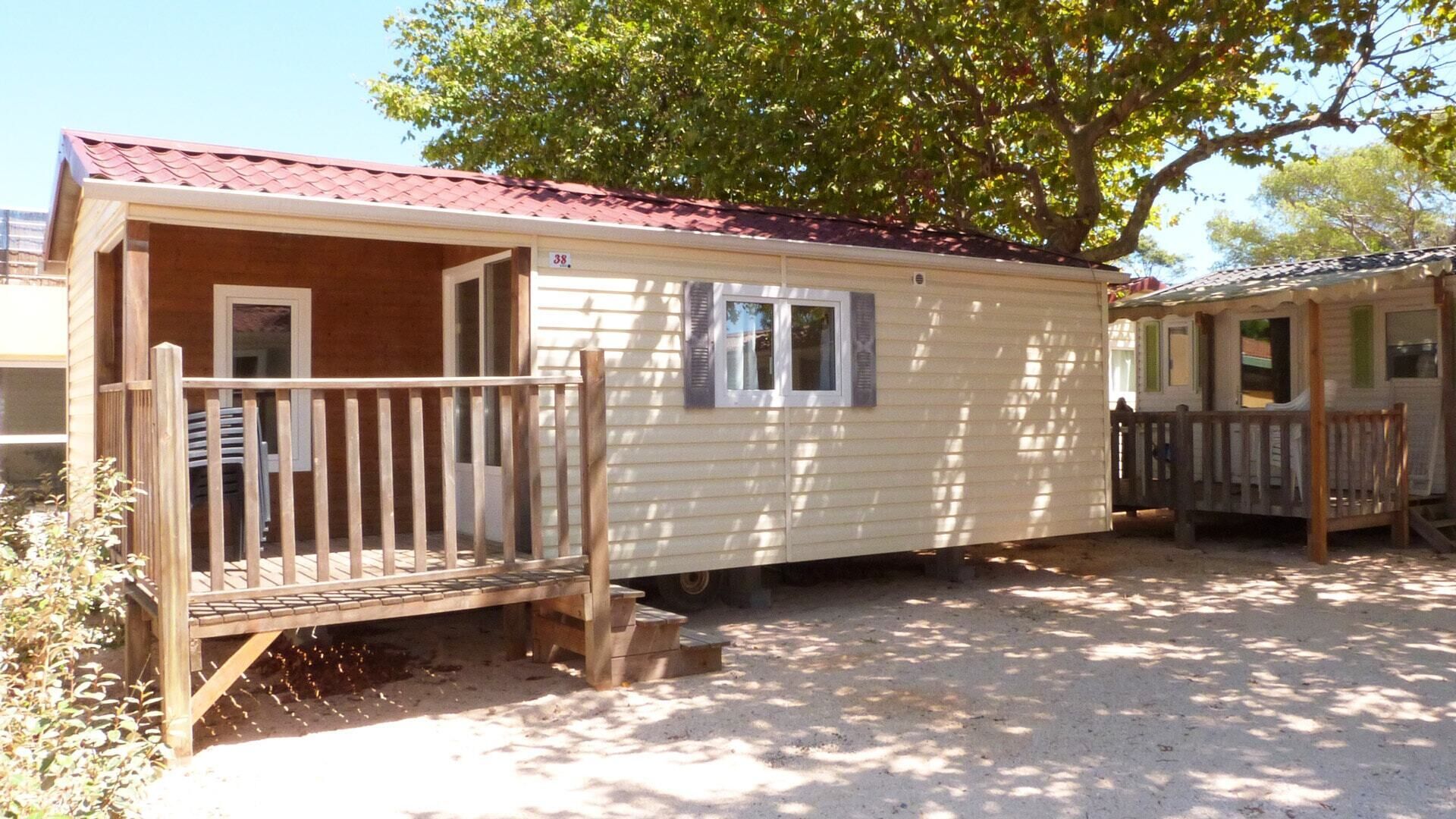 A mobile home with a wooden deck, a small porch, and a window.