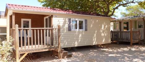 A mobile home with a wooden deck, a small porch, and a window.