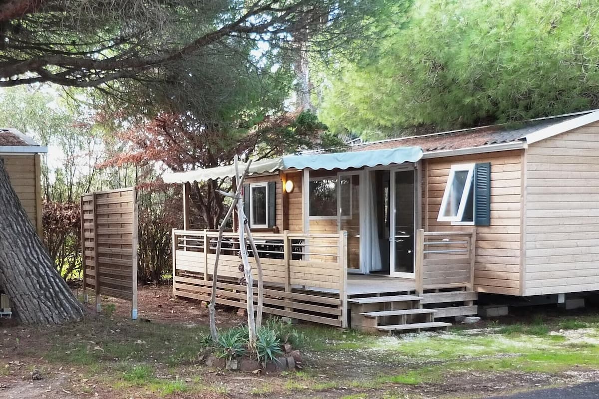 A small wooden cabin with a porch, a sliding door, and a window.