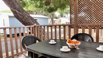 Un área de estar al aire libre techada, con una mesa, sillas y una cesta de naranjas.