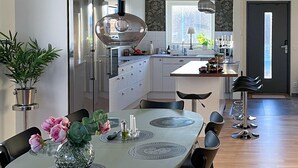 A modern kitchen with white cabinets, a central island, and a dining area with a round table and chairs.