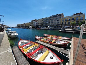 Ein Yachthafen mit mehreren kleinen Booten, einem hölzernen Steg und Gebäuden im Hintergrund.