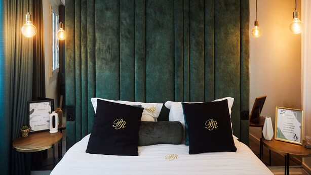 A hotel room with a bed, dark green curtains, and two bedside lamps. - Family-sized apartments to spend quality time in Guimarães. (Guimarães)