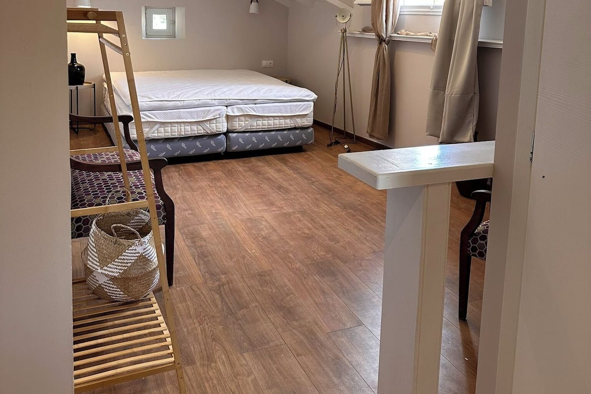 Une chambre avec un plafond en pente, un lit, une petite table et une fenêtre avec des rideaux.