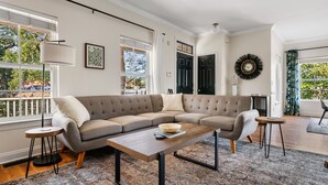 Ein Wohnzimmer mit einem Ecksofa, einem Couchtisch aus Holz und einem gemusterten Teppich.